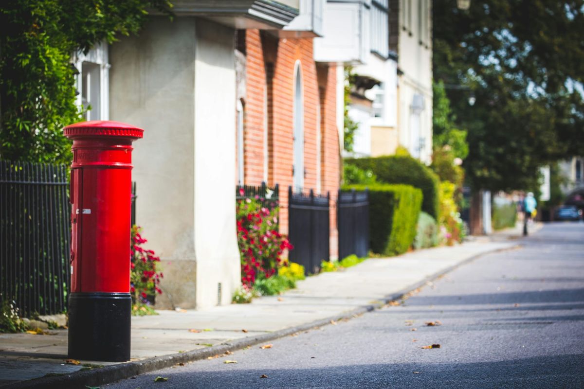 Image of british red post box and pretty street going into distance