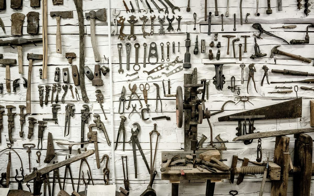 Hundreds of different tools on hooks on a white wall