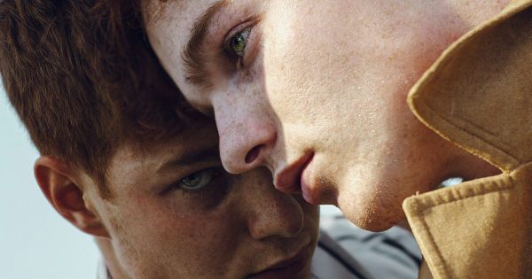 Two young red-haired men, one resting his cheek against the other's temple