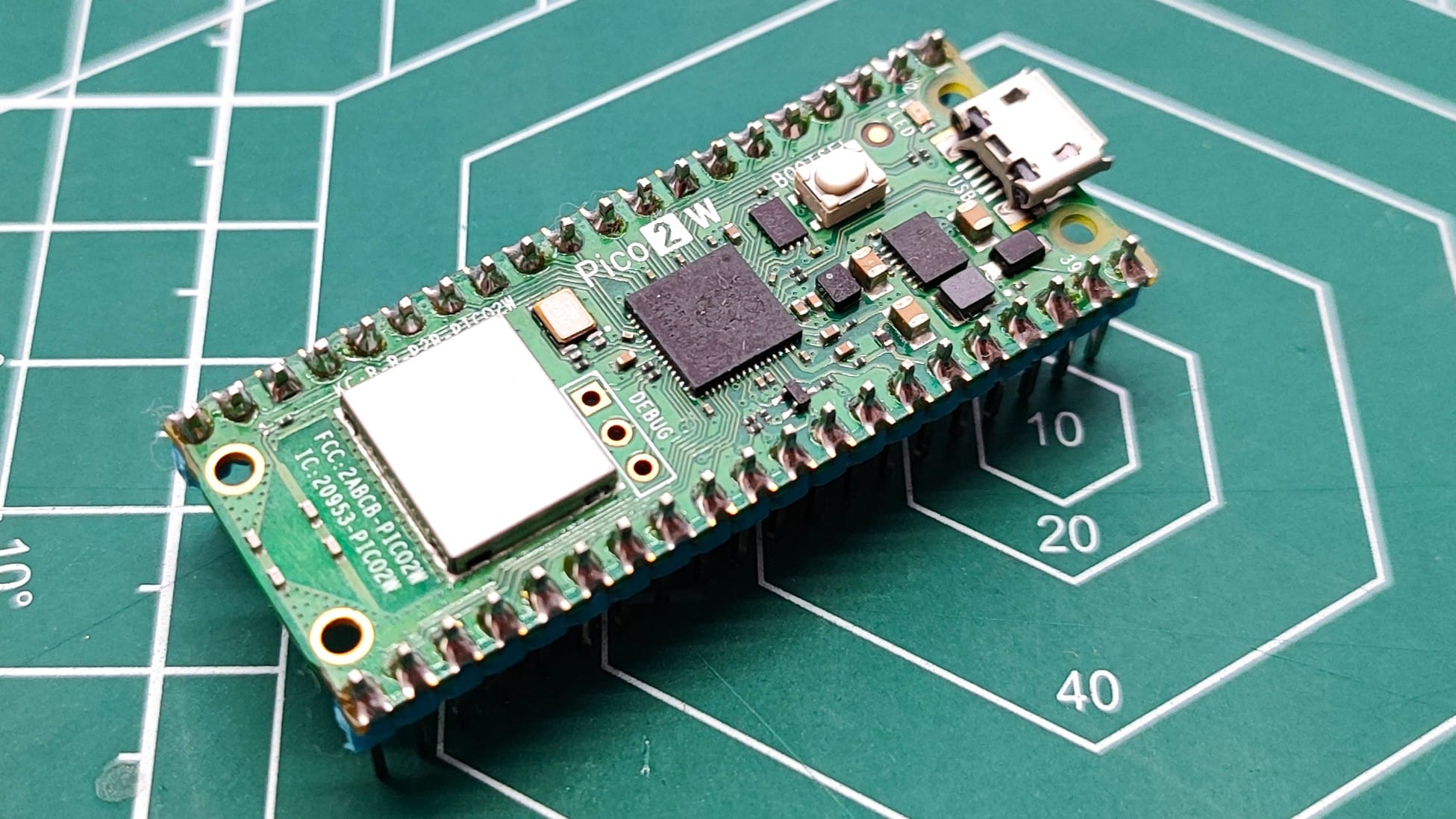A Raspberry Pi Pico 2 W on a green cutting mat background