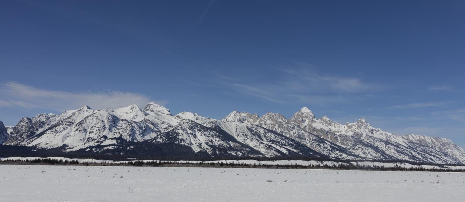 The Teton Range above a wide snow-covered valley in Grand Teton National Park in winter