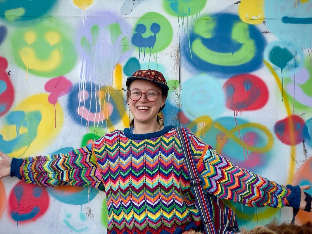 A smiling crafter in a chevron brightly colored sweater.