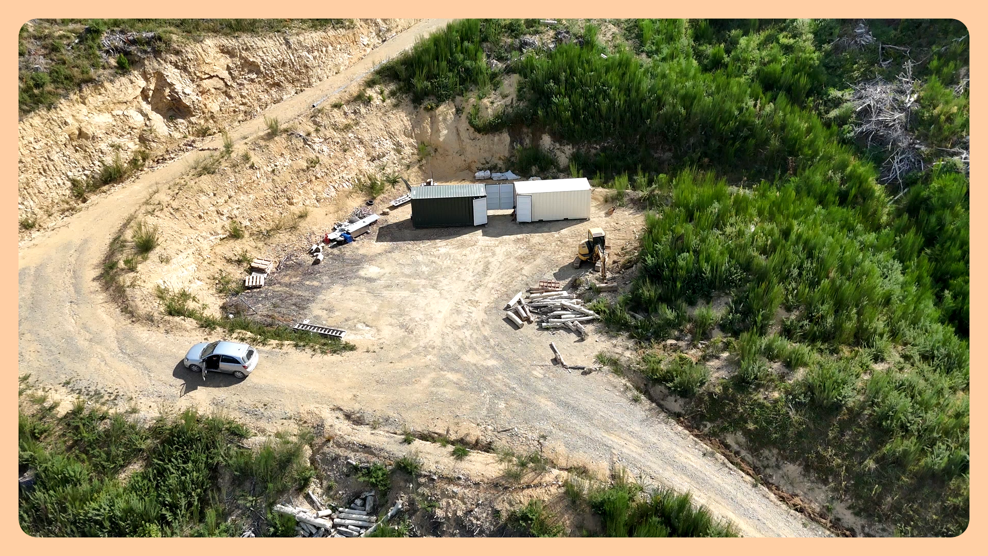 Two shipping containers used as base camp, with car parked on native forest restoration site