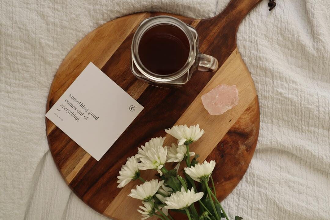Affirmation card, black coffee, flowers and crystal in bed (card by insite mind)