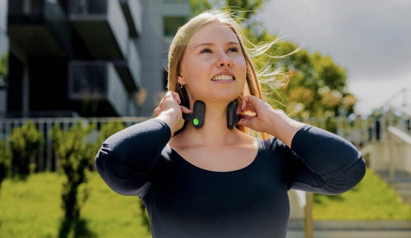 Happy woman outside using Pulsetto for panic attack, therapy for anxiety and depression