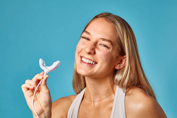 Happy woman with white teeth holding Laughland teeth whitening