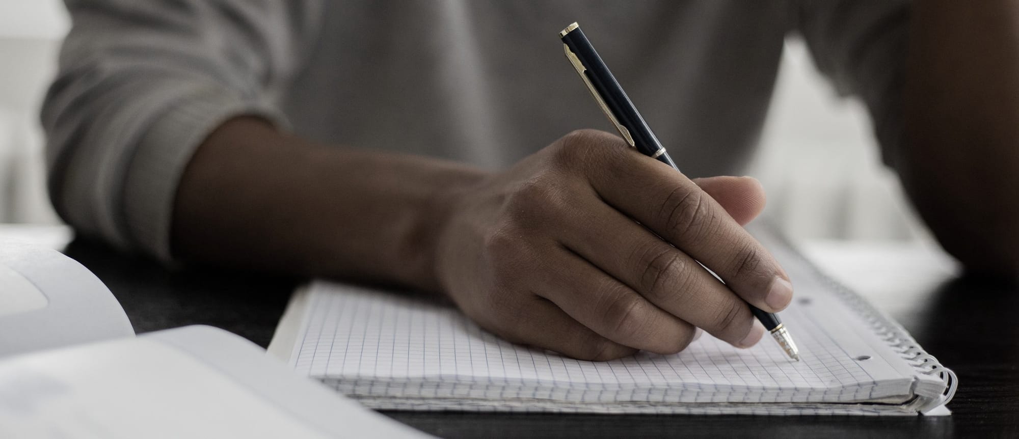 Een leerling schrijft met de hand in een geruit schrift.