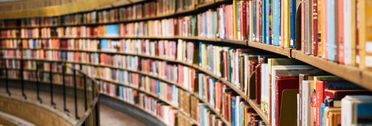 An arch of bookshelves in a library that recedes into the distance. The books are on shelves that stretch from floor to ceiling. 