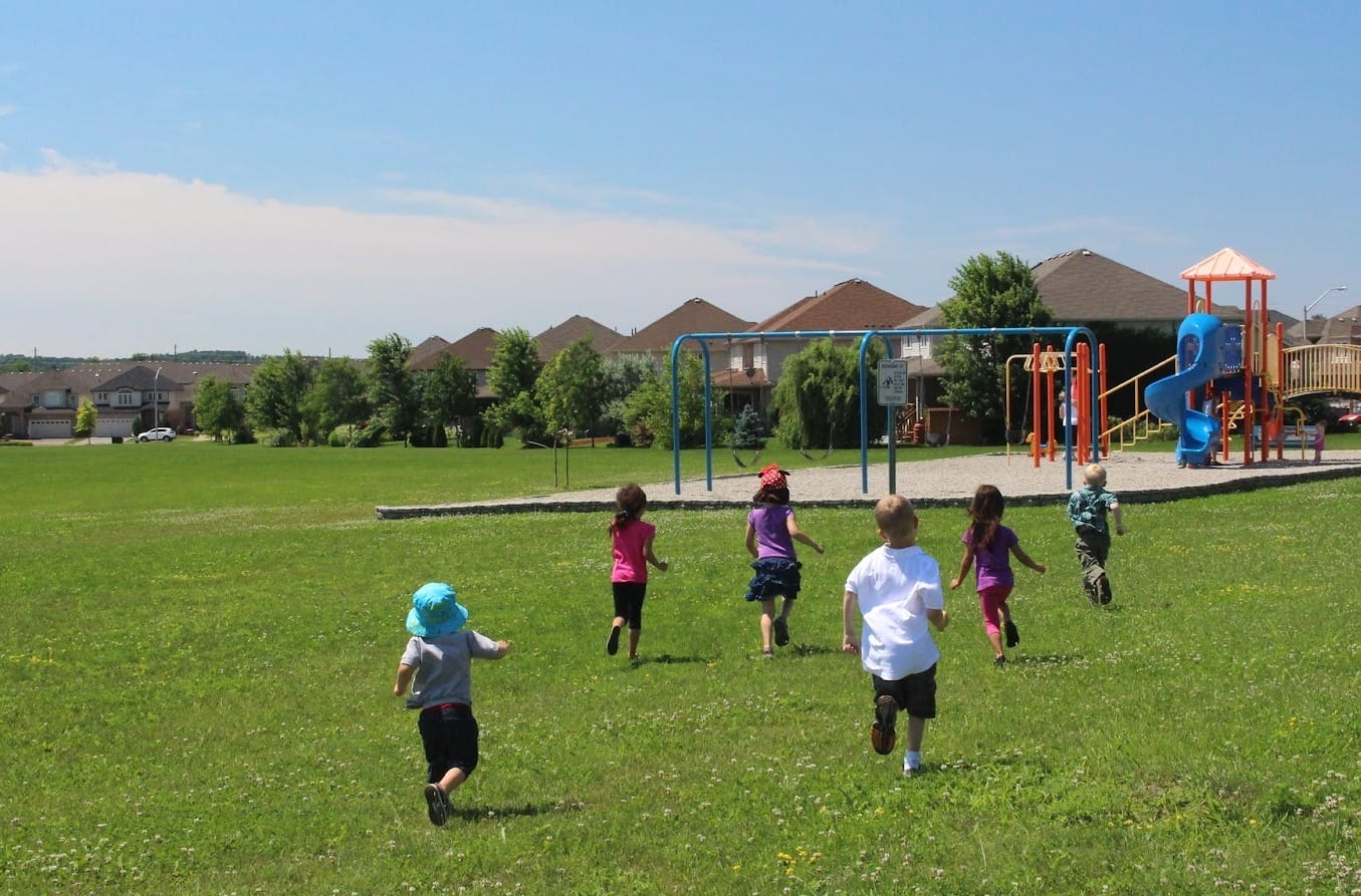 Stock photo of children running outside towards a playground.