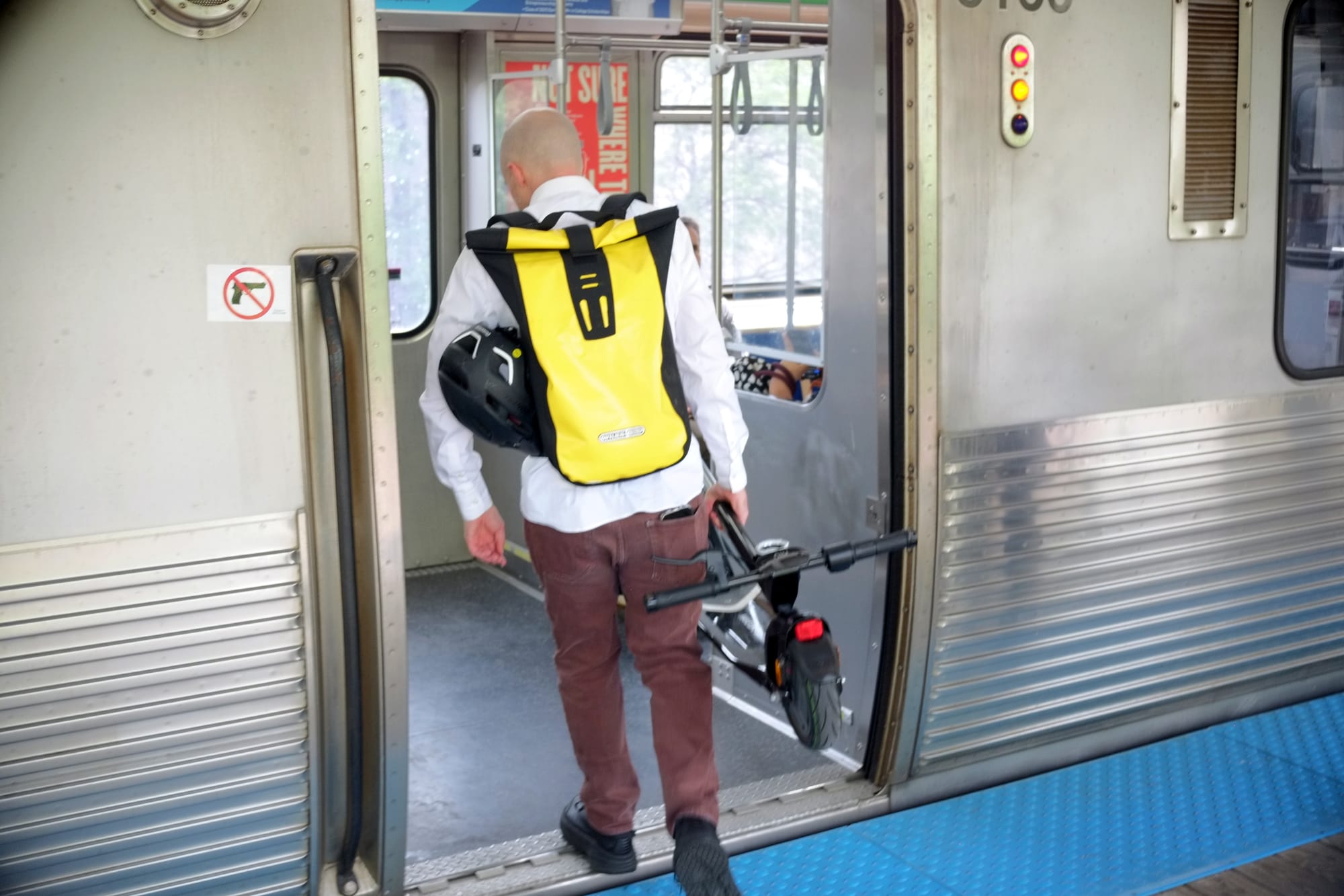A man with a bright yellow backpack, named Matthew Miller, boards a Green Line train bound for downtown from the Austin station.