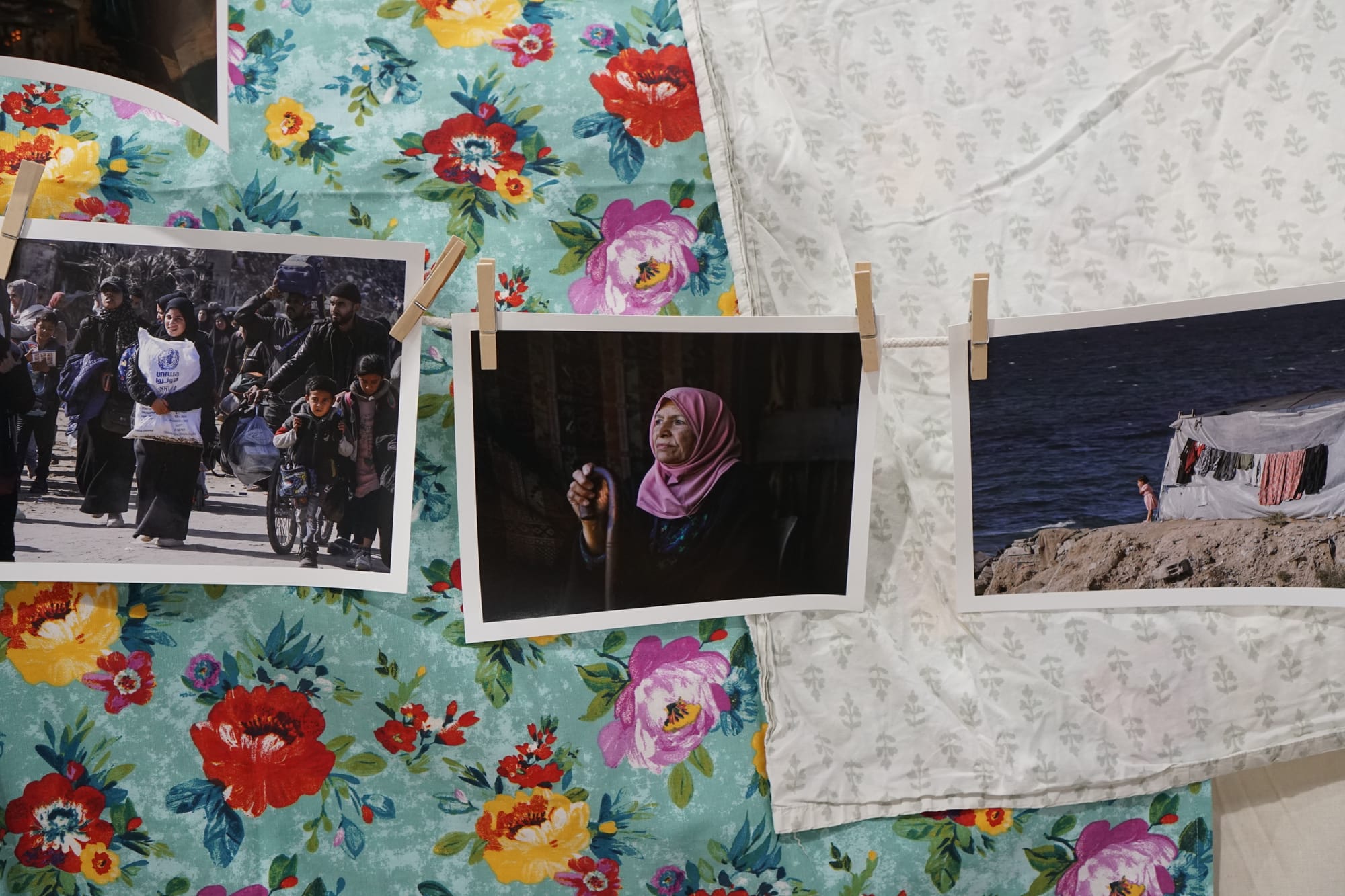 Several photographs arranged on floral-patterned fabric backgrounds. The photos show various scenes including groups of people walking, a woman in a pink hijab, and coastal scenes with laundry hanging. The fabrics feature bright flowers in turquoise, white, and navy patterns.