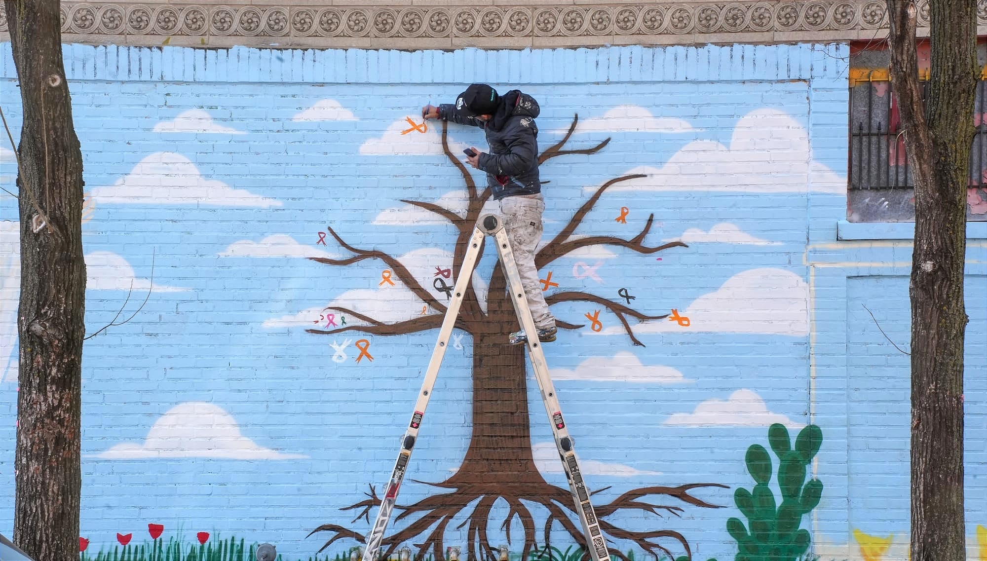 Juan Manuel Cortina paints cancer ribbons for the “En Memoria a las Víctimas de Cáncer” mural at 26th Street and Drake Avenue on Jan. 13, 2026, in Little Village. | Araceli Ramirez/15 West