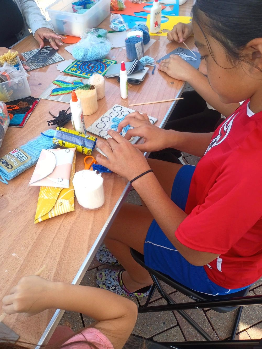 Una niña sentada haciendo manualidades con goma y papel.