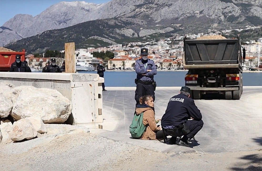 OTPOR DIVLJANJU Djevojka i pas sjeli na put kamionima koji istovaraju zemlju u more