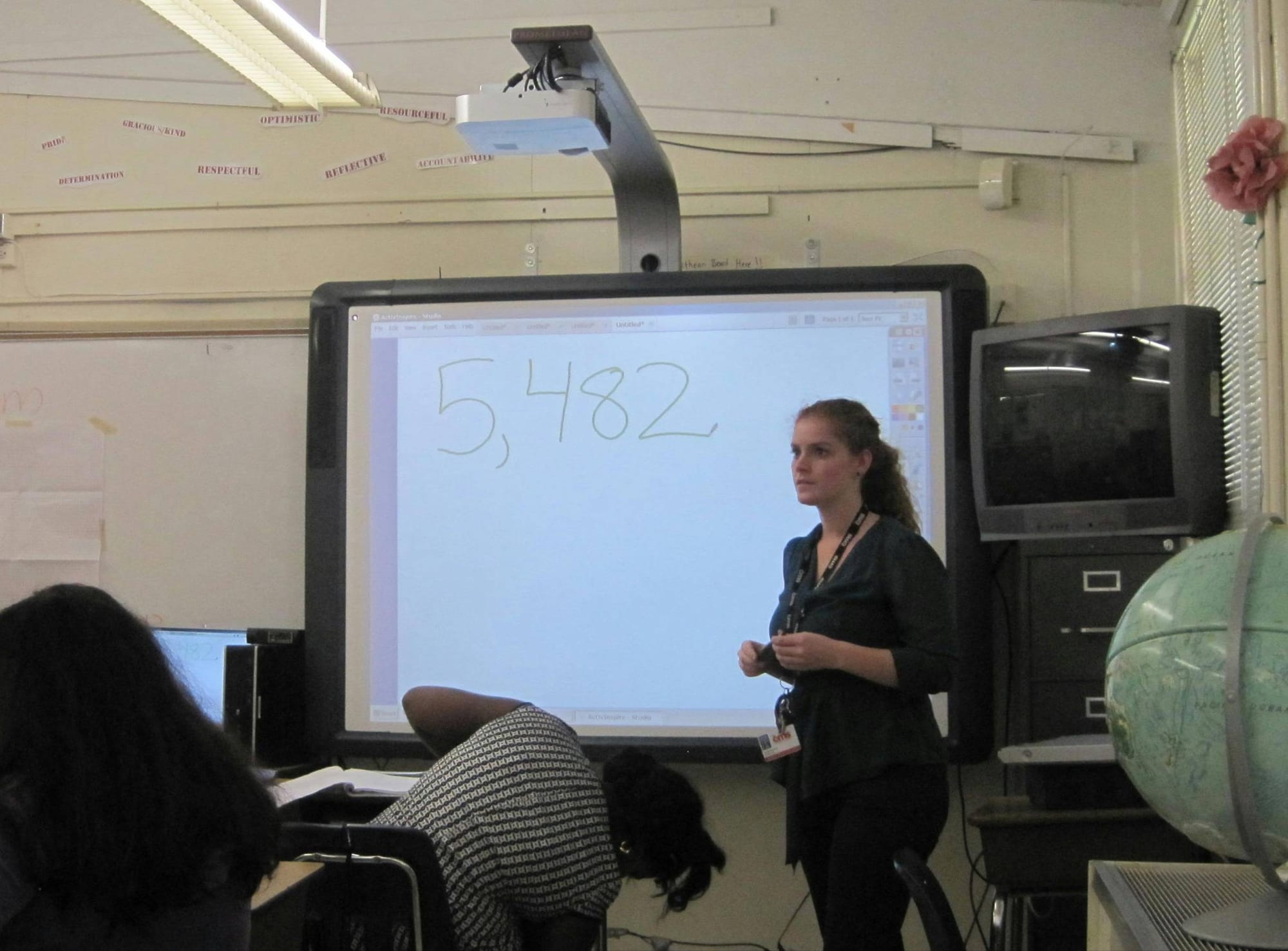 Natalie teaching math to students. One student is reaching for something outside the picture.