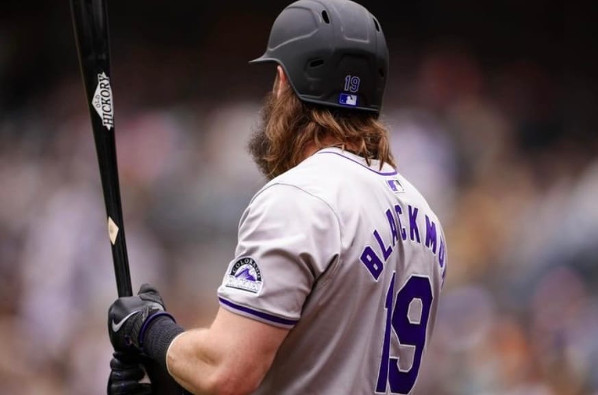 Blackmon stands with his back to the camera, holding a bat. He’s wearing a gray uniform.