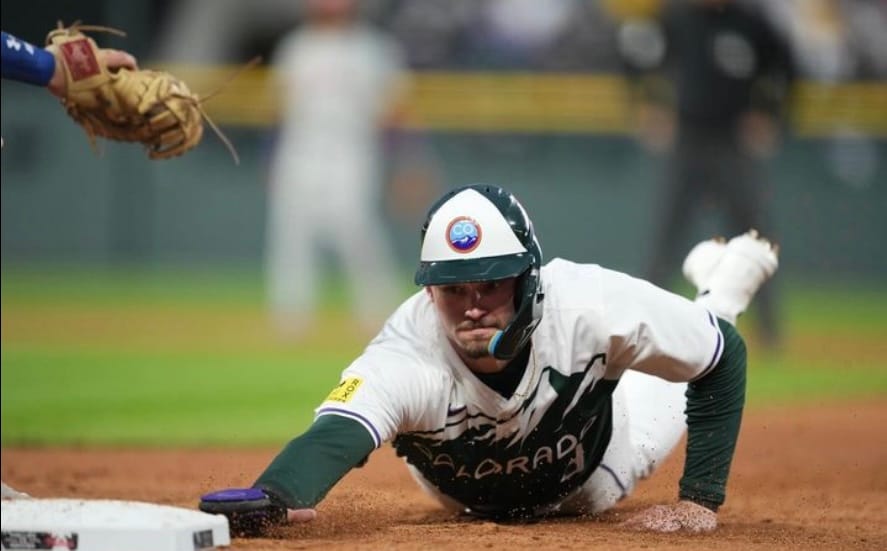 Doyle slides into third, reaching for the bag. He’s wearing the Rockies City Connect uniform.