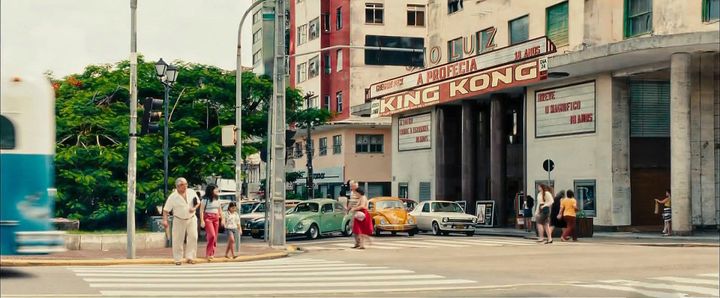 photo of the people waiting at a crosswalk across the street from the sao luiz theater with its marquee promoting king kong