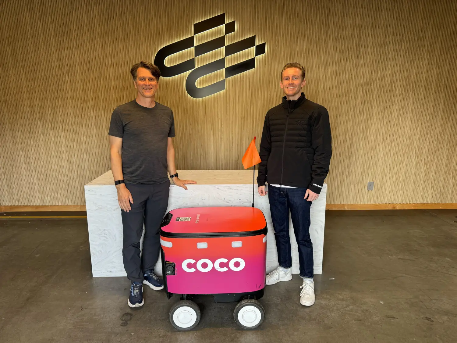 Two people standing next to a Coco robot.