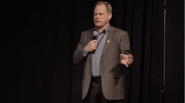 Man in a suit on a state with a microphone
