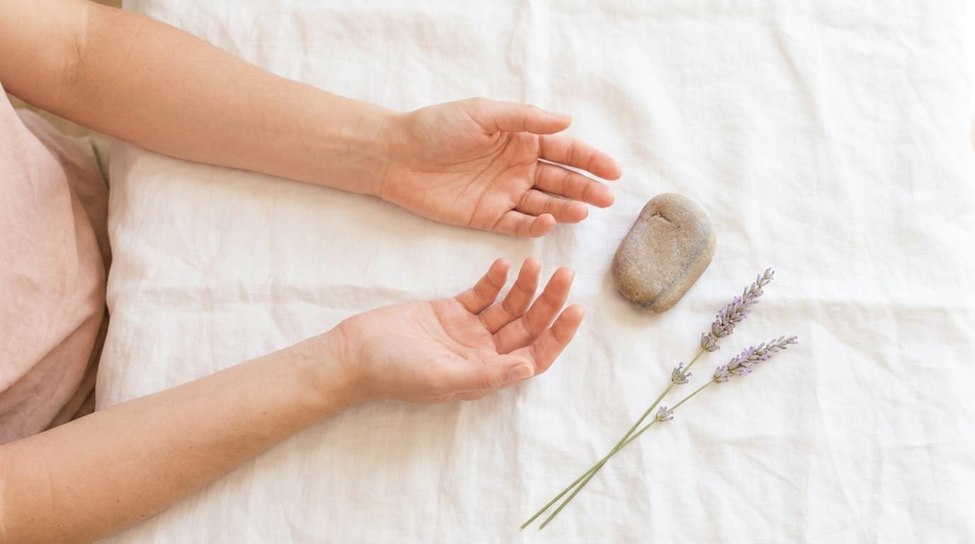 Relaxed hands resting on white linen with lavender sprig