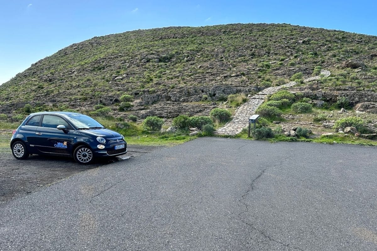 Small Blue Car In Car Park For Hiking To Ermita De San Isidro La Gomera Canary Islands Spain With Paved Path Going Up Hill In Background