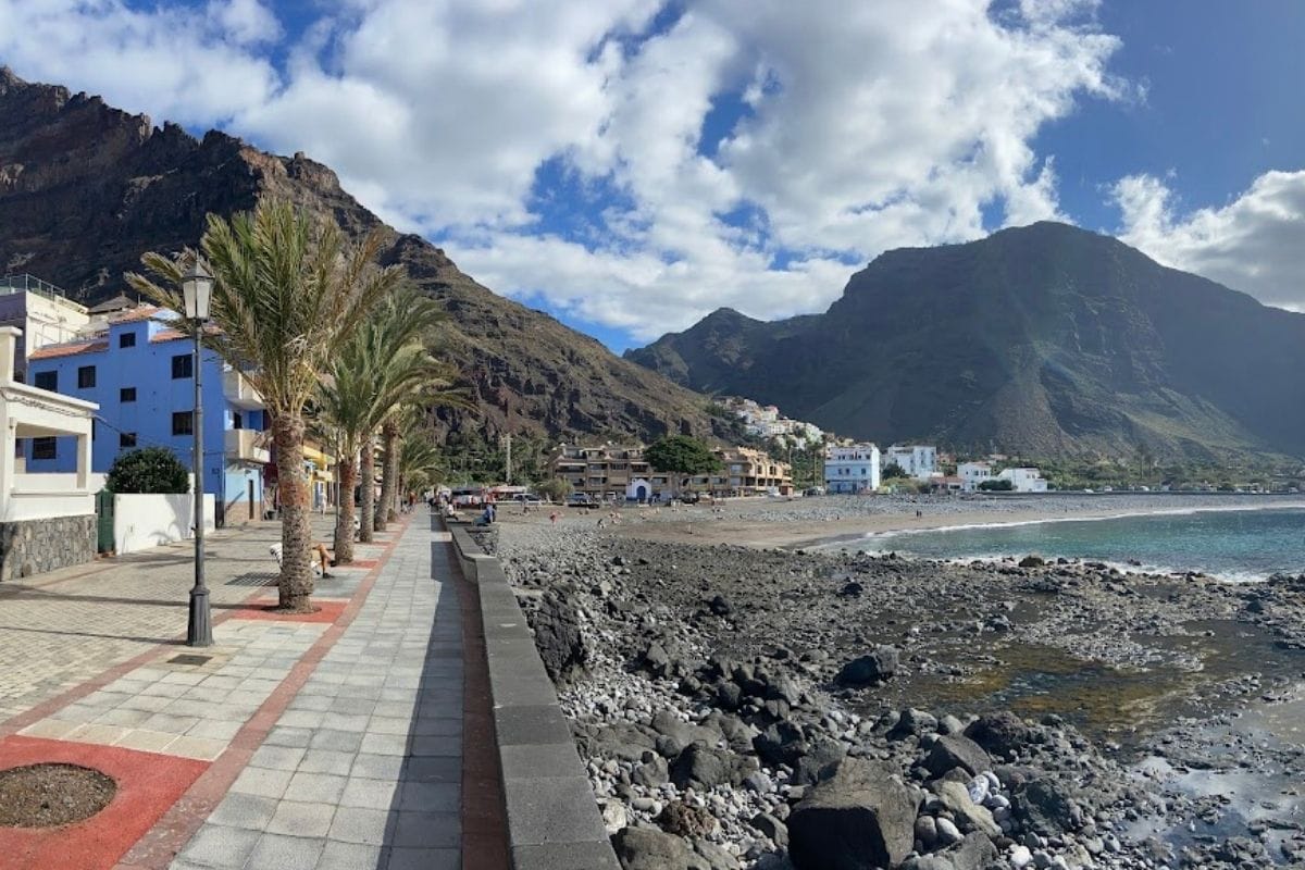 A Beach Of Sand And Pebble Called Playa De La Calera La Gomera Canary Islands Spain With A Promenade And Restaurants And Volcanic Mountains In The Background