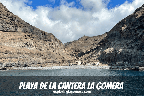 Blue Sea And A Rocky Beach With Mountains And Abandoned Buildings In Background At Playa De La Cantera La Gomera Canary Islan