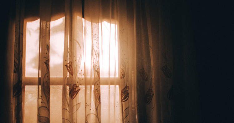 Sunlight coming through a window with sheer curtains