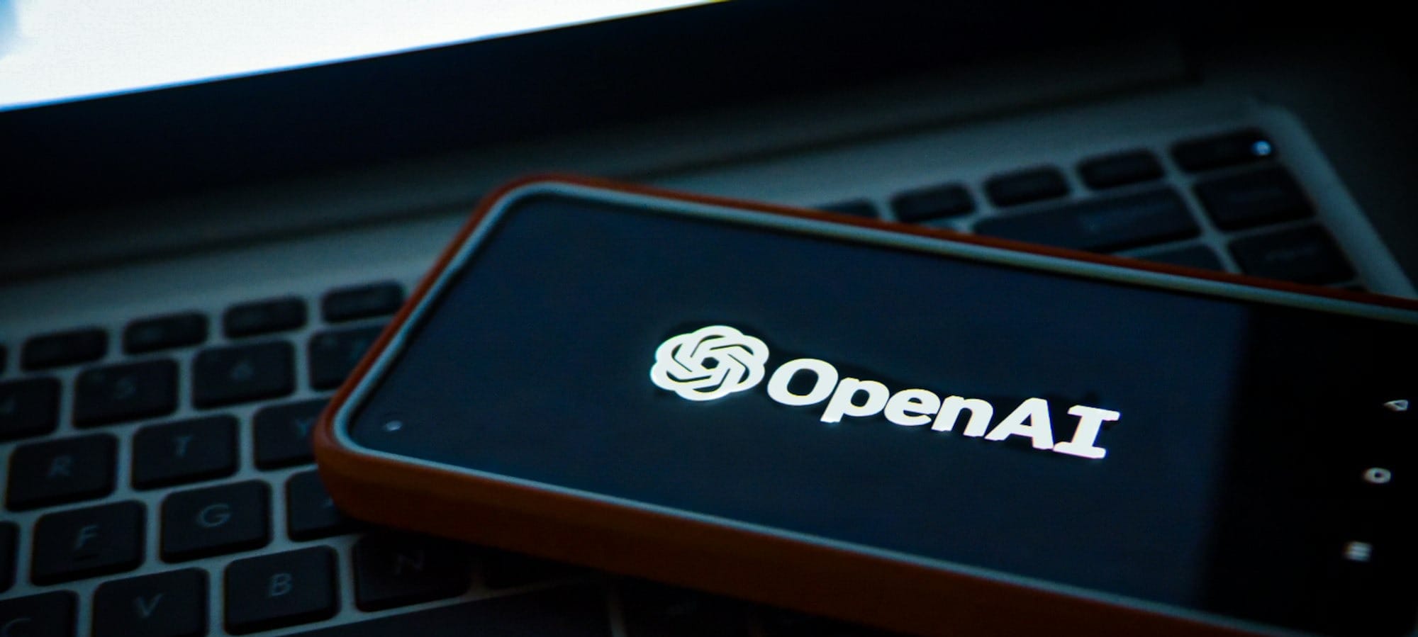 a cell phone sitting on top of a laptop computer