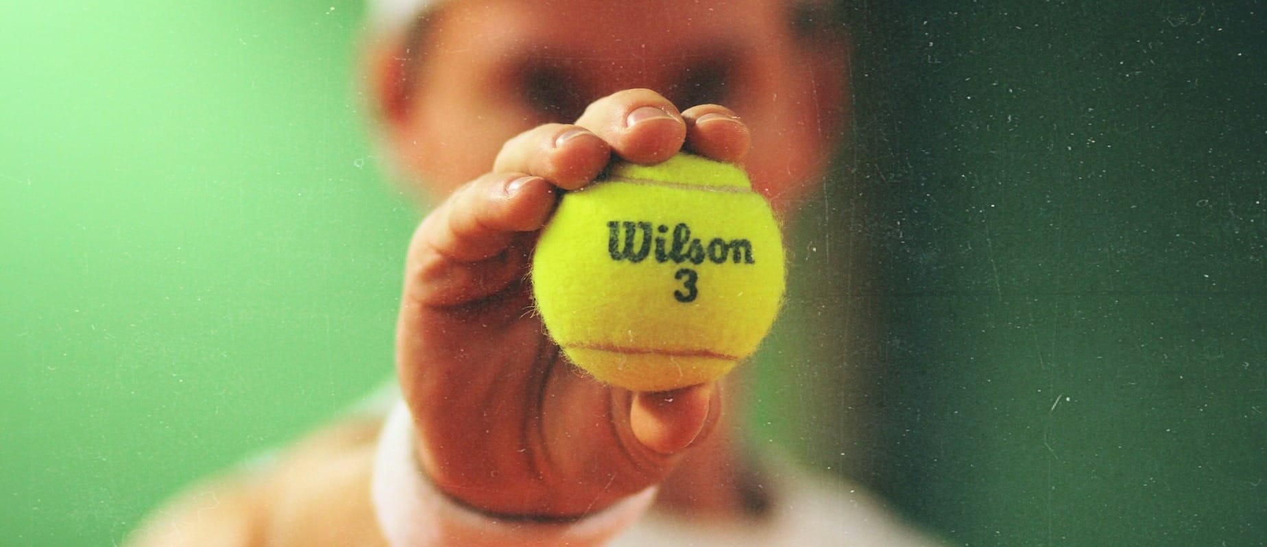 person holding green Wilson tennis ball