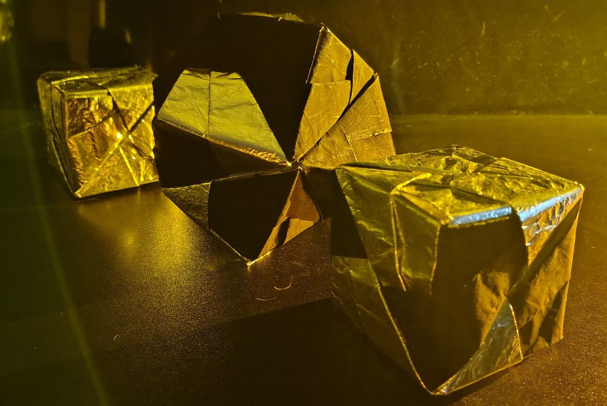 One silver cube in the background, an octahedron five-sixths pitch and one-sixth silver in the middle, and in the foreground a cube two-thirds silver and one-third pitch 