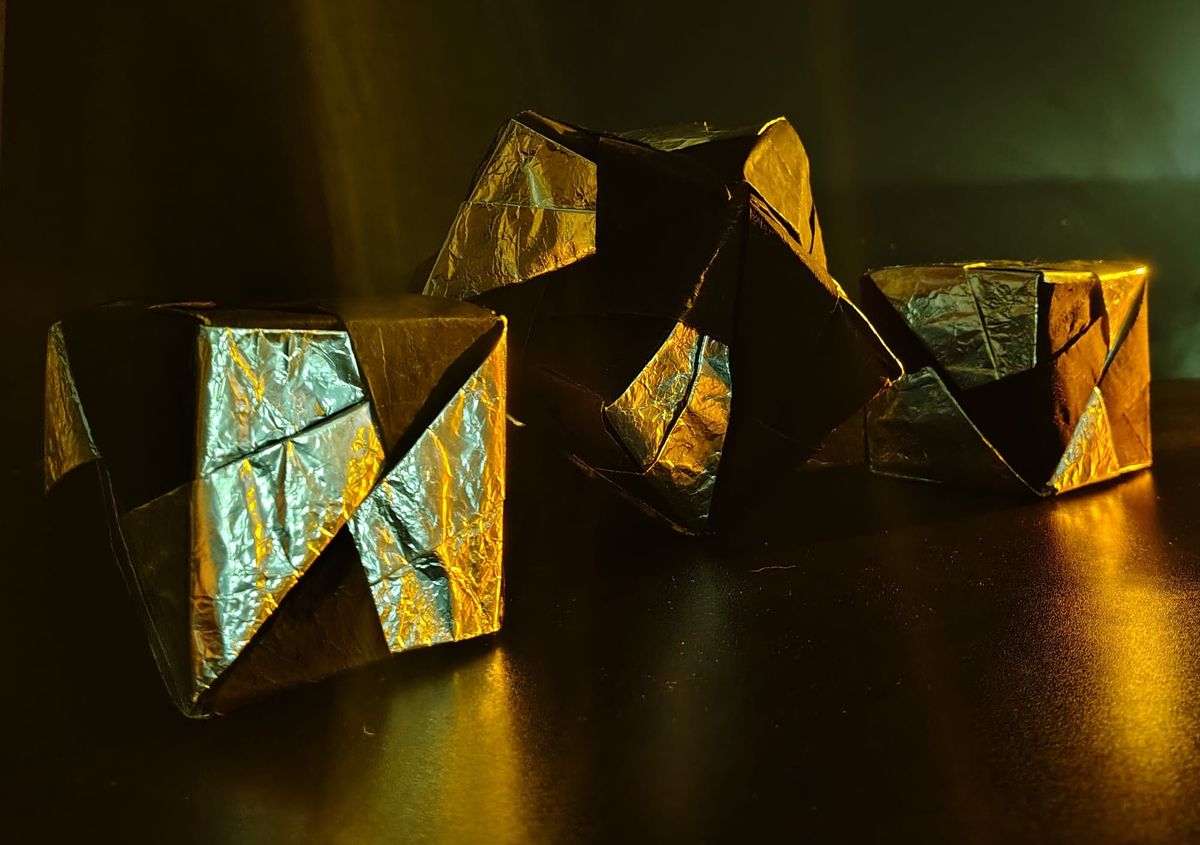 Two cubes comprised of three pitch and three silver parallelograms each around a stellated octahedron comprised of six silver and six pitch parallelograms