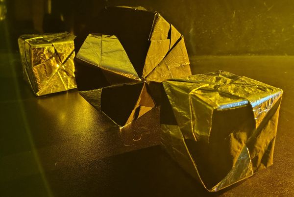 One silver cube in the background, an octahedron five-sixths pitch and one-sixth silver in the middle, and in the foreground a cube two-thirds silver and one-third pitch 