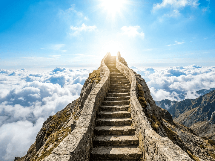 Stone staircase leading up a mountain ridge into bright sunlight above clouds