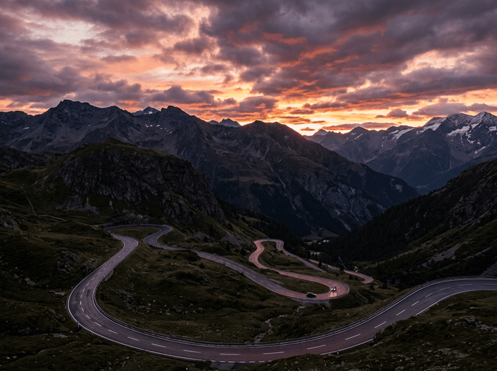 Winding mountain road with cars at sunset and dramatic clouds
