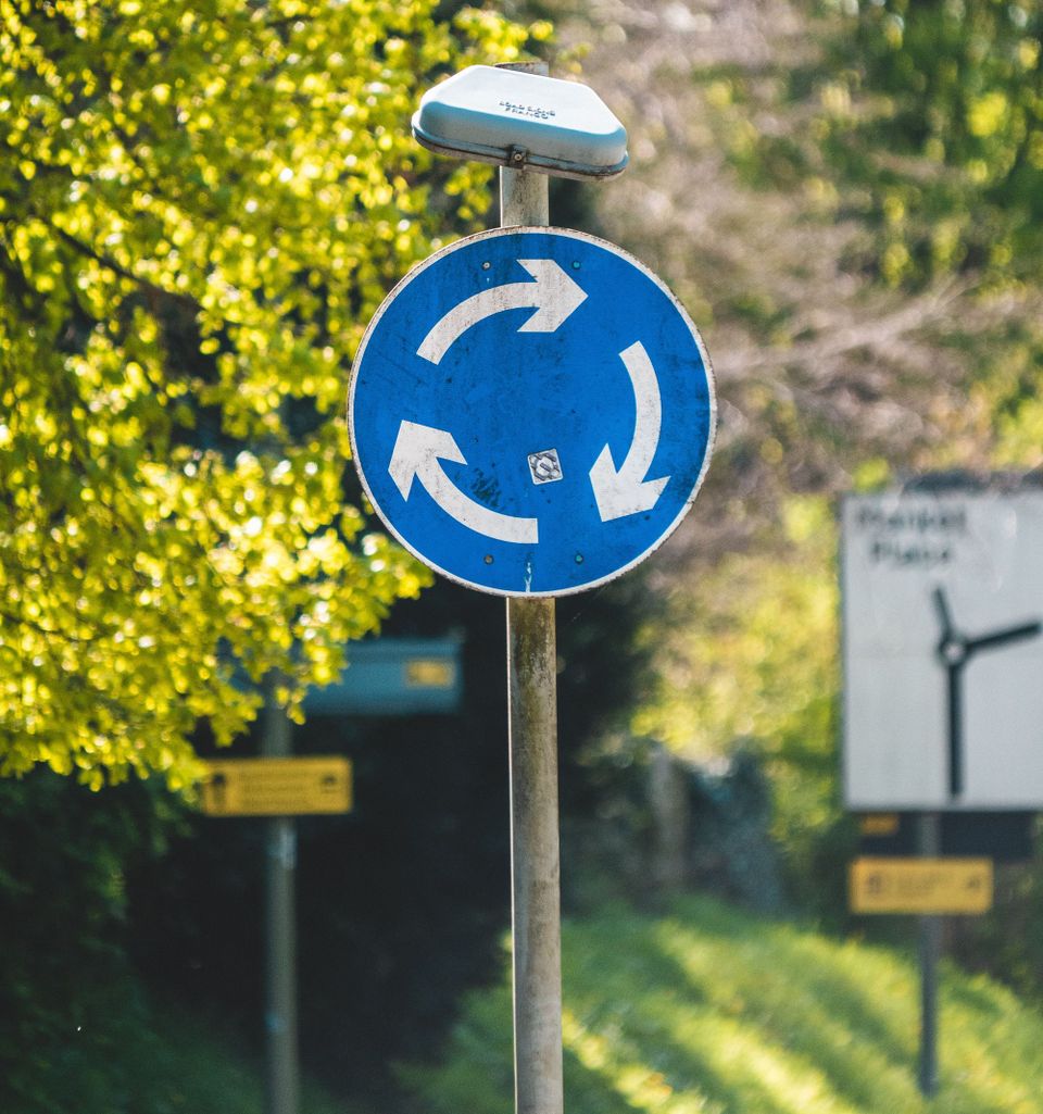Blue sign with 3 white arrows forming a circle (sign is to show a roundabout on UK roads)