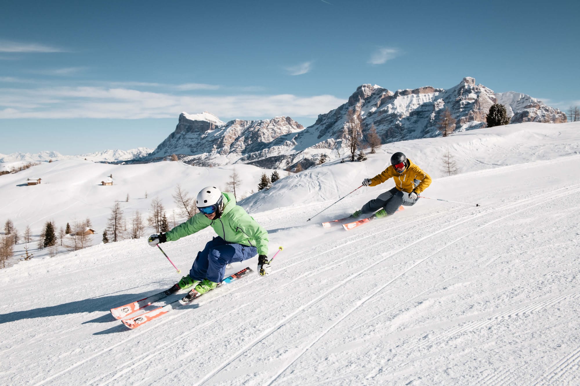 Skiers turn in Alta Badia with rocky outcrop in background