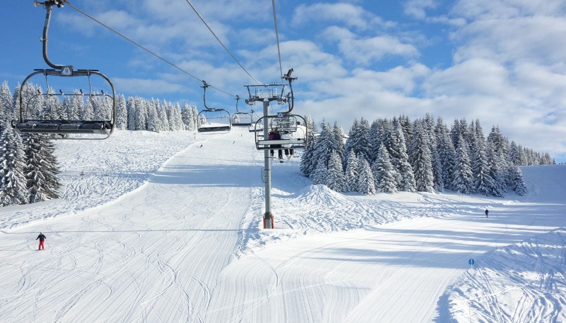 Gentle ski slopes in Portes du Soleil surrounded by trees and a chairlift