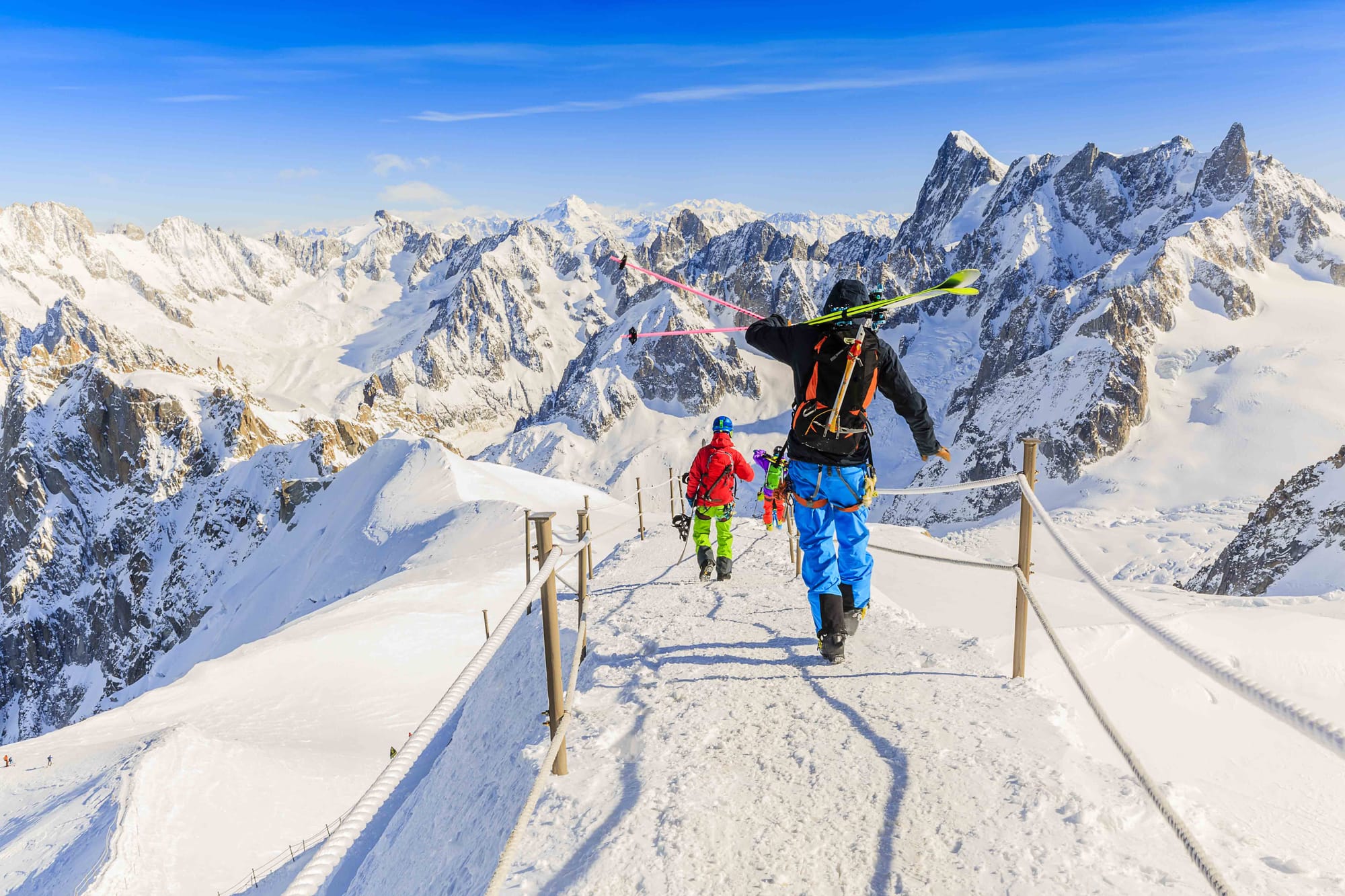 Daring off-piste skier and boarder walking to the first descent of the day at the top of the mountains.