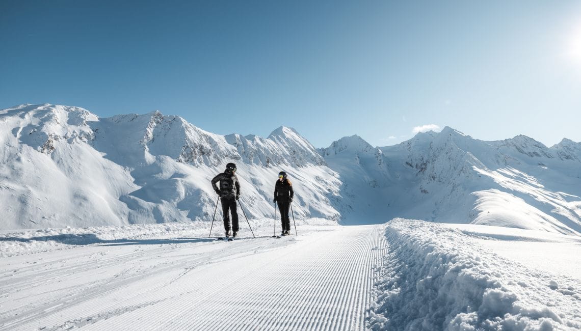 A couple of skiers travel across a very high piste