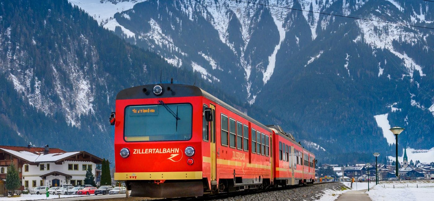 Red train trundles towards Mayrhofen ski resort in Austria with dramatic mountain scenery