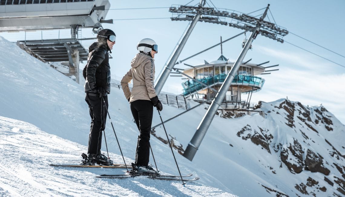 TOP Mountain Star in the distance as people stand on skis in foreground