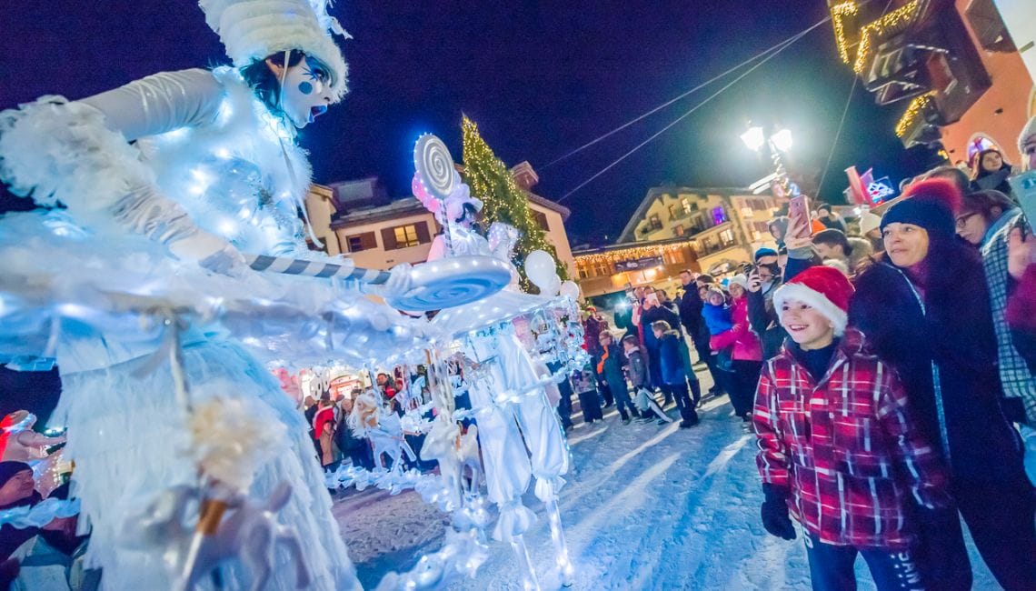 People dressed in a white outfit entertain families in Les Arcs Christmas parade