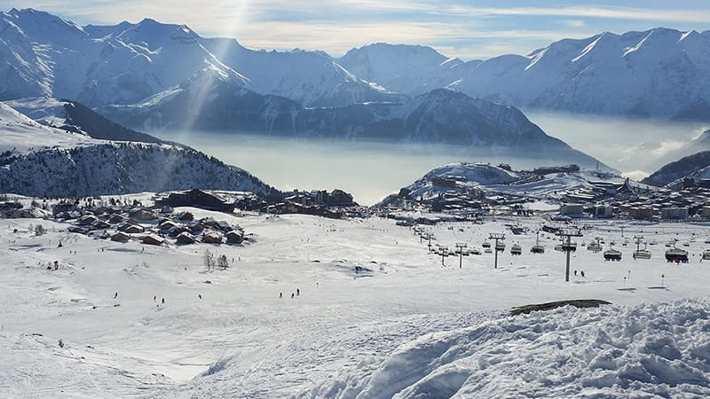 View from slopes surrounding Alpe d'Huez with chairlift and dramatic mountain backdrop