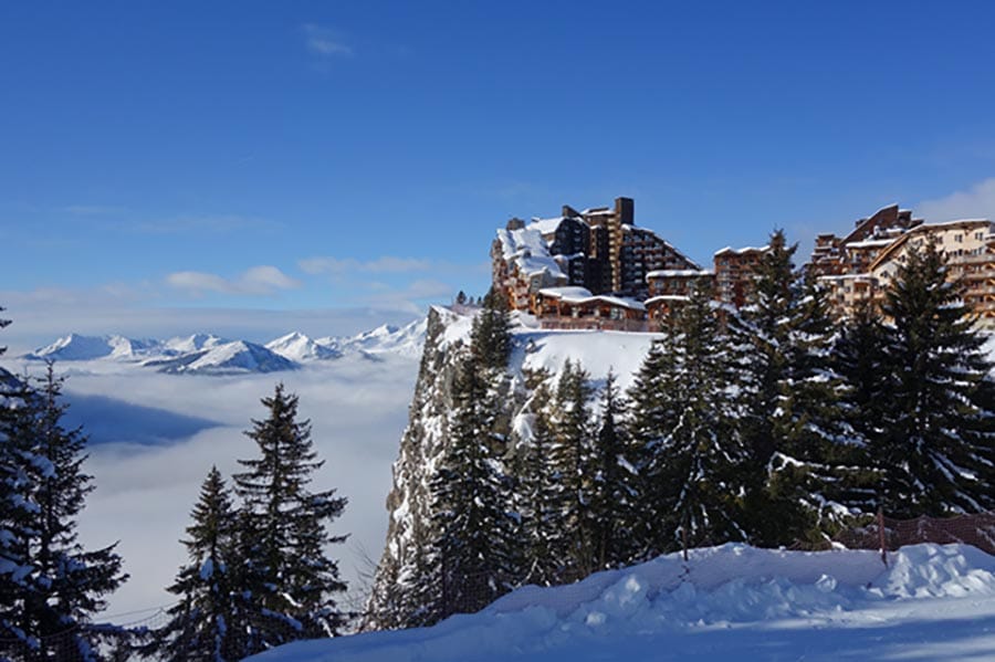 Avoriaz buildings perched on edge of clifftop with trees in front