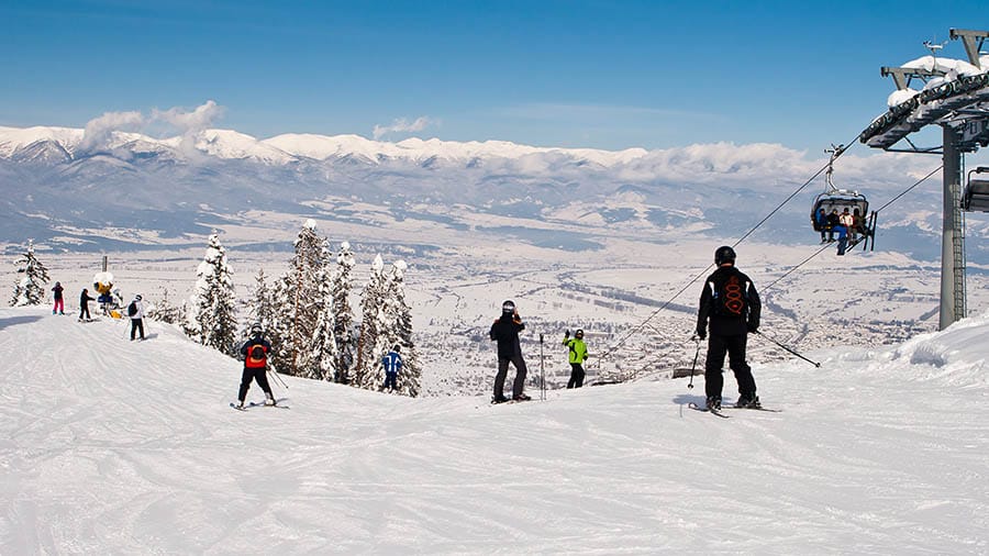 Skiers wait at top of Bansko slope with stunning panoramic view