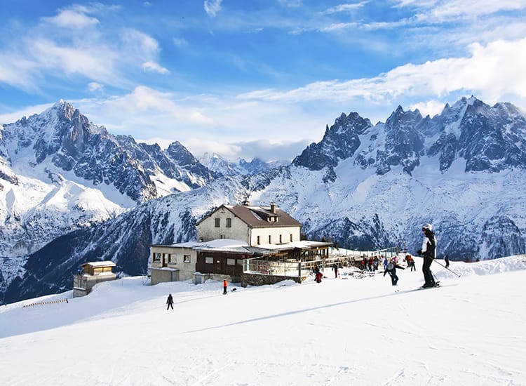 Mountain hut in Chamonix with dramatic mountain backdrop and skiers dotted about