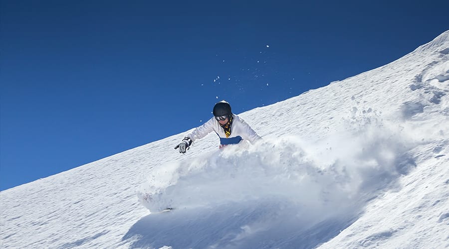 One skier off-piste skiing with blues skies