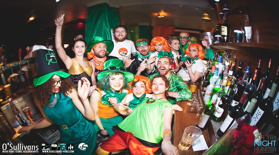 People dress in Irish clothes and crowd round a bar